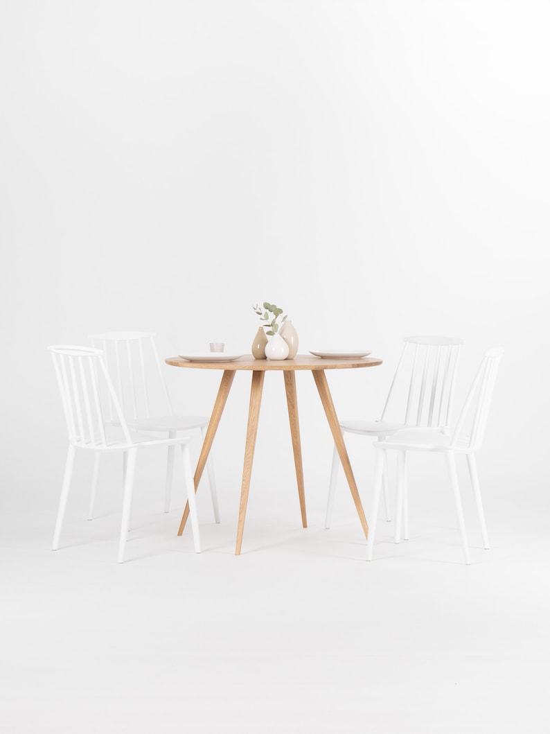 Round dining table with four solid oak legs and natural wood finish