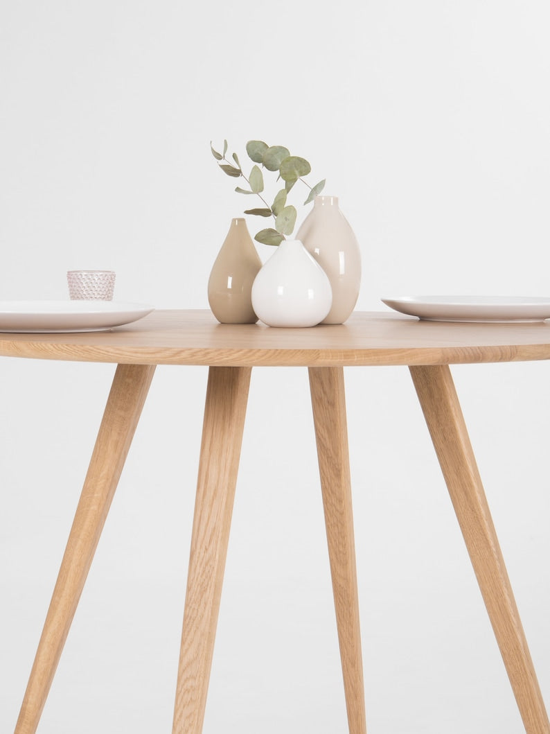 Round dining table with four solid oak legs and natural wood finish