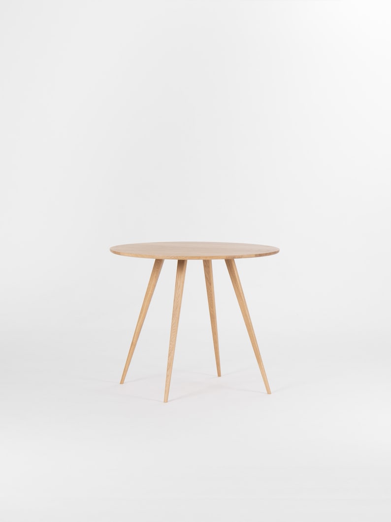 Round dining table with four solid oak legs and natural wood finish