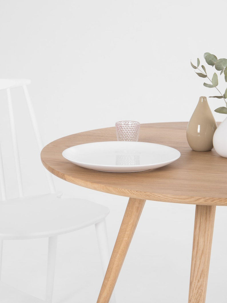 Round dining table with four solid oak legs and natural wood finish