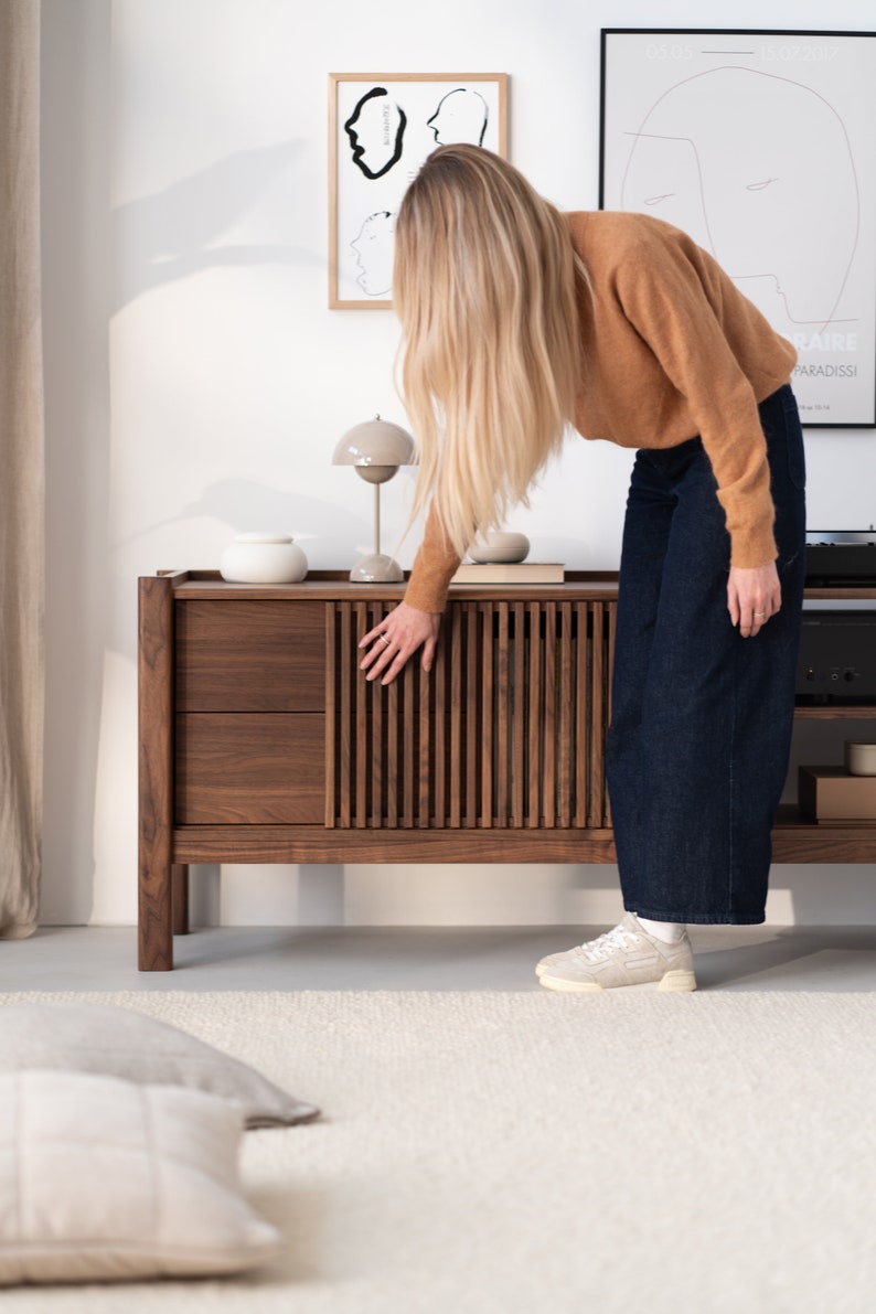 Wide walnut TV console with slatted doors, drawers, and cable management