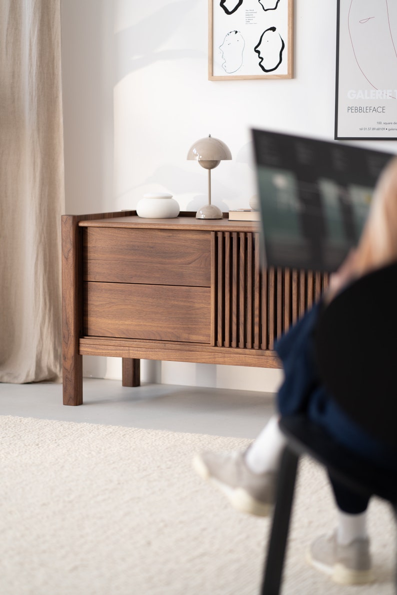 Wide walnut TV console with slatted doors, drawers, and cable management