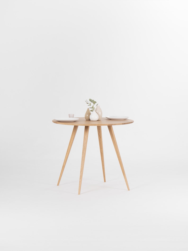 Round dining table with four solid oak legs and natural wood finish