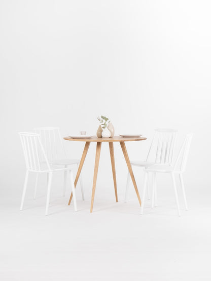 Round dining table with four solid oak legs and natural wood finish