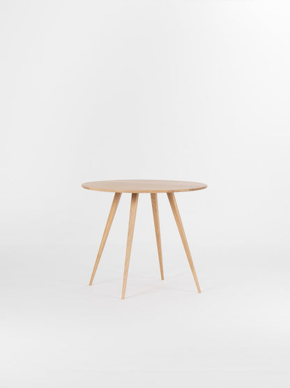 Round dining table with four solid oak legs and natural wood finish